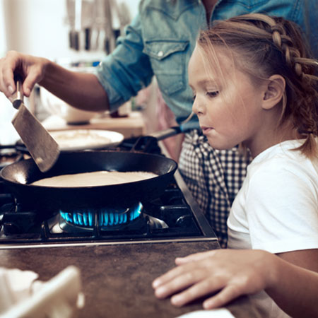 Enfant et sa mère qui cuisinent au gaz