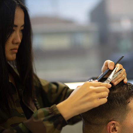 Coiffeuse en train de couper les cheveux d’un homme