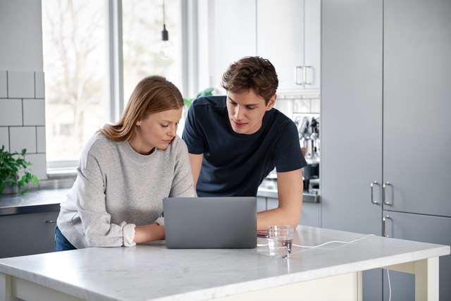 Couple sur leur ordinateur portable dans la cuisine 
