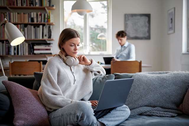 Homme et femme derrière leur ordinateur dans le salon