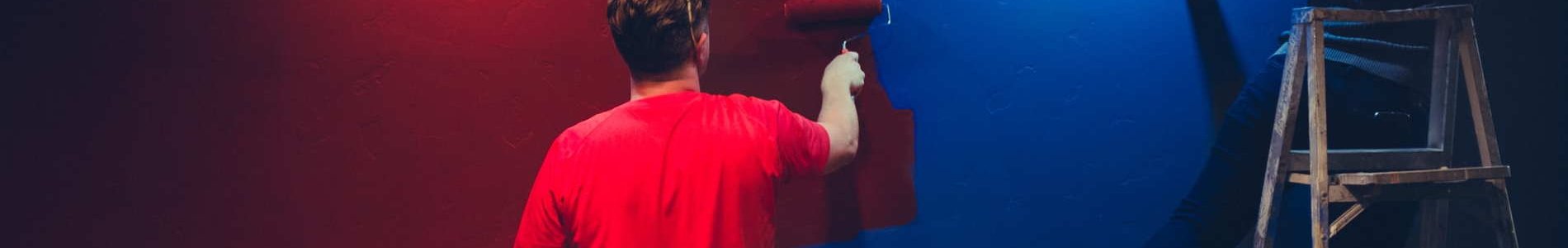 Deux personnes qui peignent un mur rouge et bleu