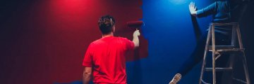 Deux personnes qui peignent un mur rouge et bleu